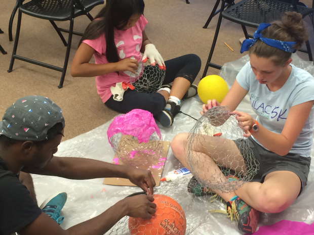 Hailey, Justis and Kyonna use chicken wire and tissue papier-mâché to make colored rocks.