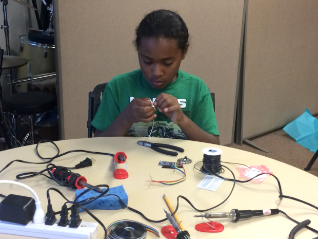 Raymond tins the tips of the wires using solder.